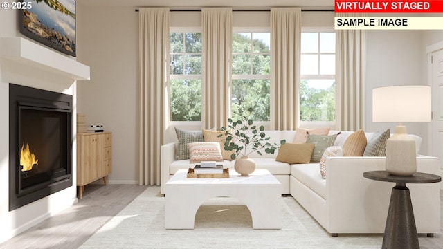 living room with light wood finished floors, baseboards, and a glass covered fireplace