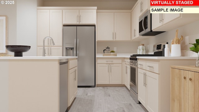 kitchen featuring stainless steel appliances, a sink, white cabinets, light countertops, and light wood-type flooring