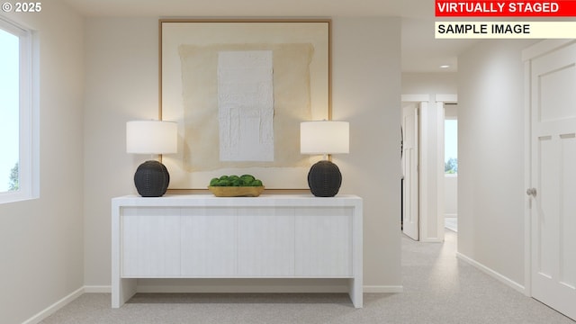 hallway featuring light colored carpet and baseboards