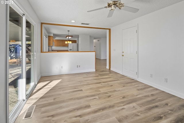 unfurnished living room with ceiling fan, a textured ceiling, and light hardwood / wood-style floors