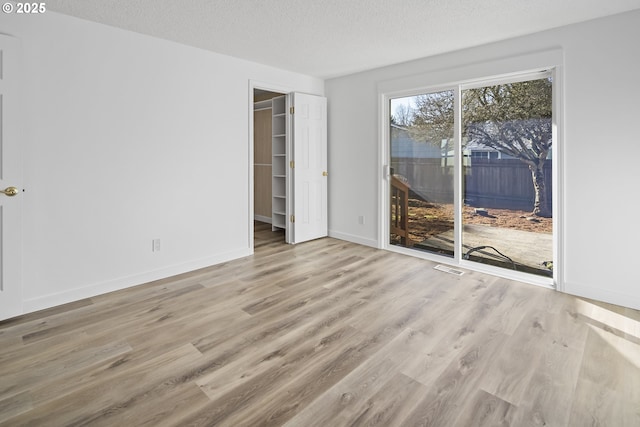 unfurnished room with a textured ceiling and light hardwood / wood-style flooring