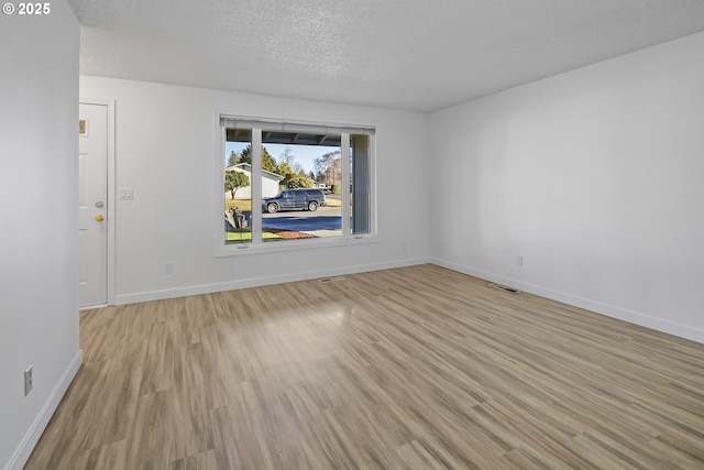 unfurnished room with light hardwood / wood-style floors and a textured ceiling