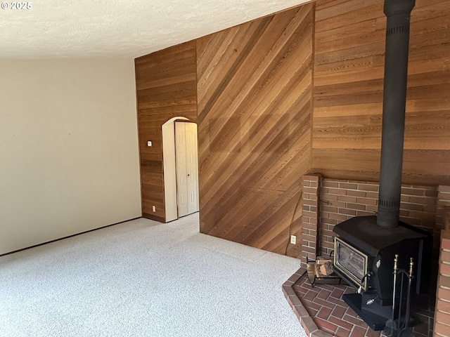 2040 40th St, Florence, OR 97439 - unfurnished living room with a wood stove, wooden walls, carpet flooring, and a textured ceiling