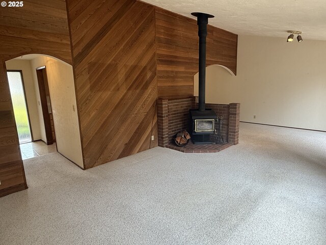 2040 40th St, Florence, OR 97439 - unfurnished living room with a wood stove, wooden walls, arched walkways, and carpet flooring