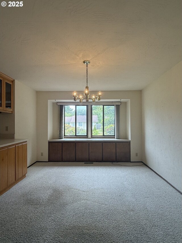 2040 40th St, Florence, OR 97439 - unfurnished dining area with a chandelier, carpet floors, and a textured ceiling