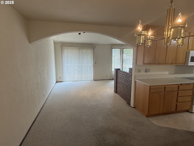 2040 40th St, Florence, OR 97439 - kitchen with arched walkways, light countertops, a chandelier, light carpet, and white microwave