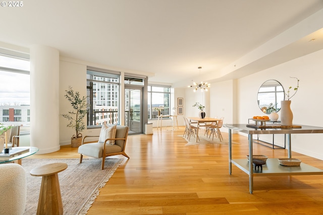 living area with a notable chandelier, floor to ceiling windows, and light wood-type flooring