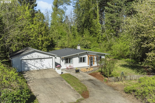 view of front of house featuring fence, a garage, a chimney, and driveway
