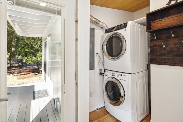 laundry area with estacked washer and dryer, light wood finished floors, and baseboards