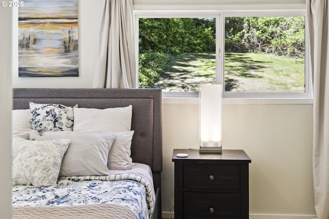bedroom featuring multiple windows and a textured wall