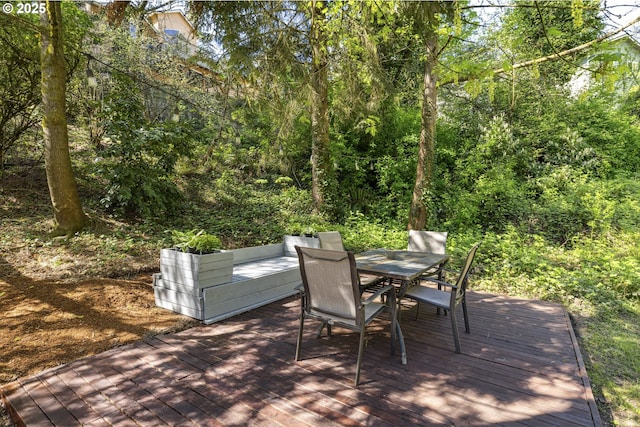 wooden deck with outdoor dining space and a forest view