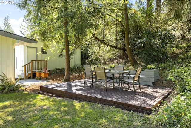 view of grassy yard featuring outdoor dining space and a wooden deck