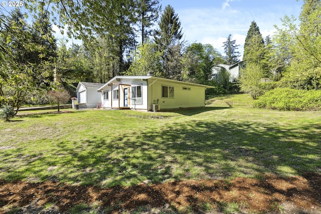 view of front of home featuring a front yard, cooling unit, and view of wooded area