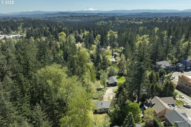 drone / aerial view of a heavily wooded area and a mountainous background