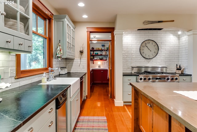 kitchen featuring light wood finished floors, recessed lighting, glass insert cabinets, a sink, and stove
