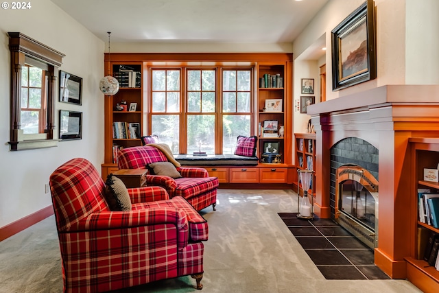 living area featuring a fireplace with flush hearth, carpet floors, and baseboards