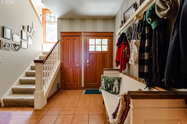 foyer with baseboards, stairway, and light tile patterned floors