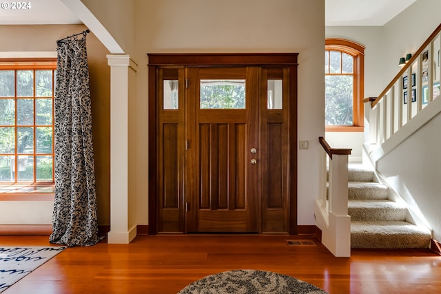 entryway featuring visible vents, a wealth of natural light, wood finished floors, and stairs