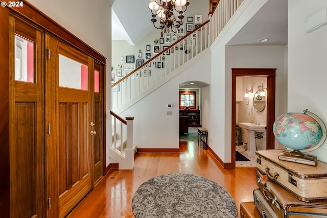 entrance foyer with light wood-style flooring, a chandelier, baseboards, stairs, and arched walkways