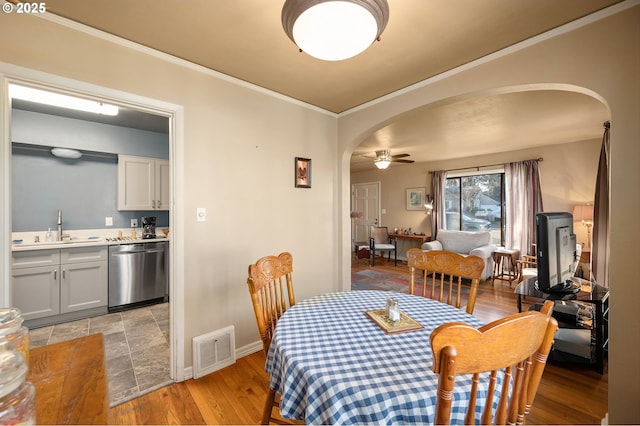 dining space featuring crown molding, sink, ceiling fan, and light hardwood / wood-style flooring