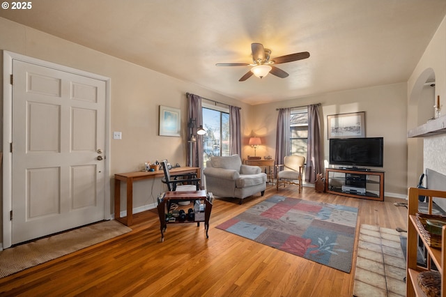 living room with ceiling fan, wood-type flooring, and a fireplace