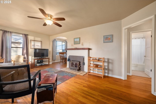 living room featuring a wood stove, hardwood / wood-style floors, and ceiling fan