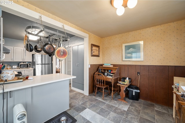 kitchen with white cabinetry, decorative light fixtures, appliances with stainless steel finishes, kitchen peninsula, and radiator