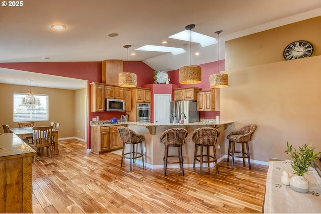 755 NW 23rd St, Pendleton, OR 97801 - kitchen with stainless steel appliances, a kitchen breakfast bar, a peninsula, light wood-style flooring, and brown cabinets