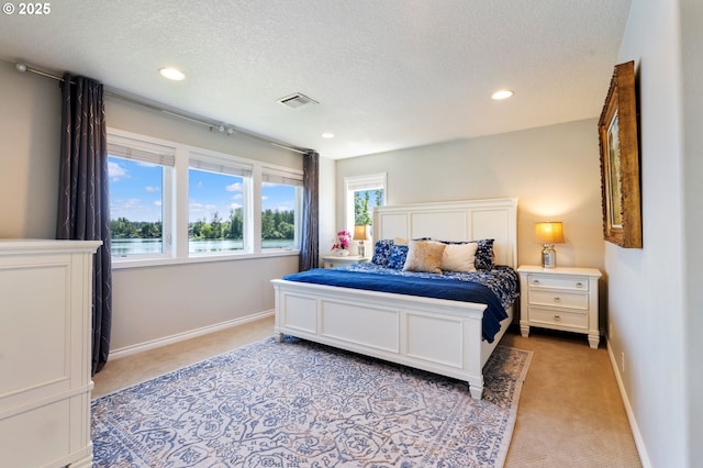 bedroom with light colored carpet, a textured ceiling, baseboards, recessed lighting, and a water view