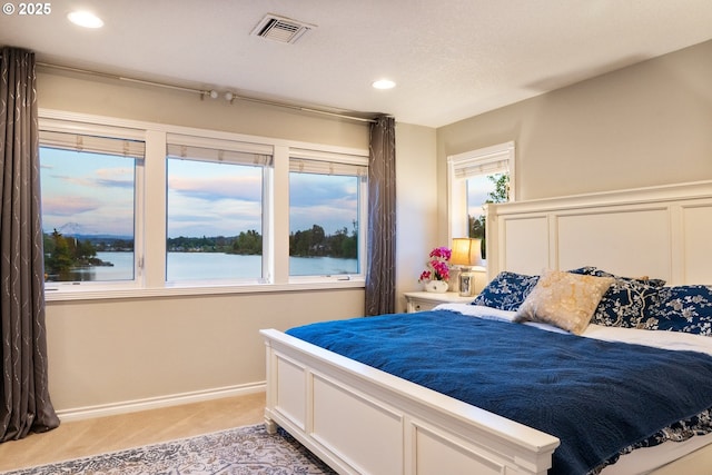 bedroom featuring light carpet, recessed lighting, baseboards, and a water view