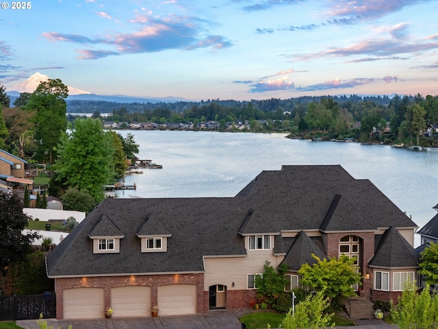 view of front of home with brick siding, a water view, and a garage