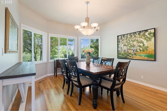 dining room featuring light wood finished floors, a chandelier, and baseboards