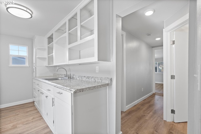 kitchen with sink, white cabinets, and light wood-type flooring