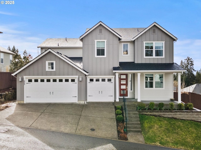 view of front of house with a shingled roof, concrete driveway, covered porch, fence, and board and batten siding