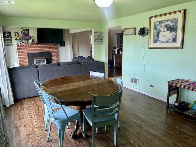 dining area featuring dark hardwood / wood-style flooring and a brick fireplace