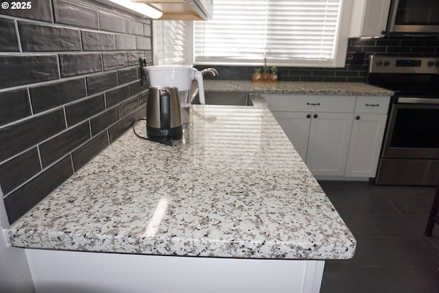 kitchen featuring a sink, white cabinets, appliances with stainless steel finishes, a wealth of natural light, and tasteful backsplash