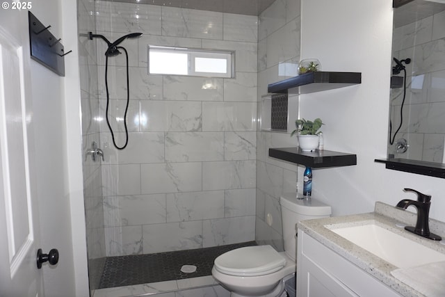 full bathroom with a tile shower, vanity, and toilet