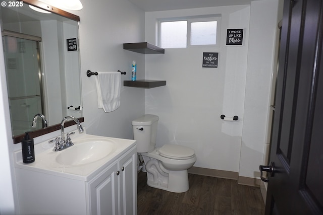 full bathroom with a shower with door, toilet, vanity, wood finished floors, and baseboards