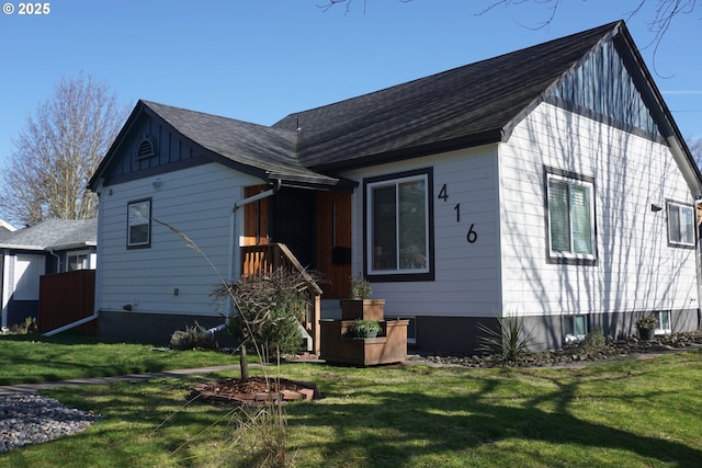 rear view of house with a yard and roof with shingles