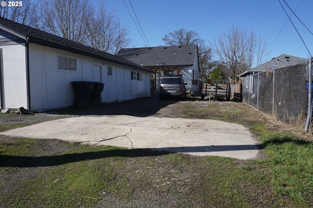 exterior space featuring board and batten siding, fence, and driveway