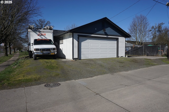 view of property exterior with a garage, driveway, and fence