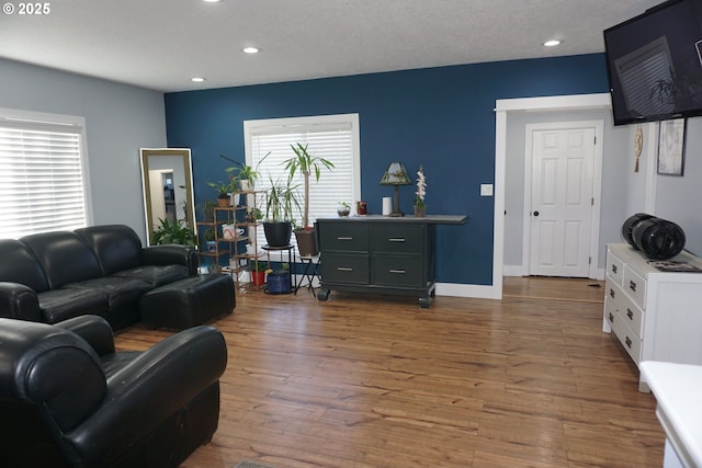 living area featuring a textured ceiling, baseboards, wood finished floors, and recessed lighting