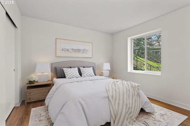 bedroom with a closet, baseboards, and wood finished floors