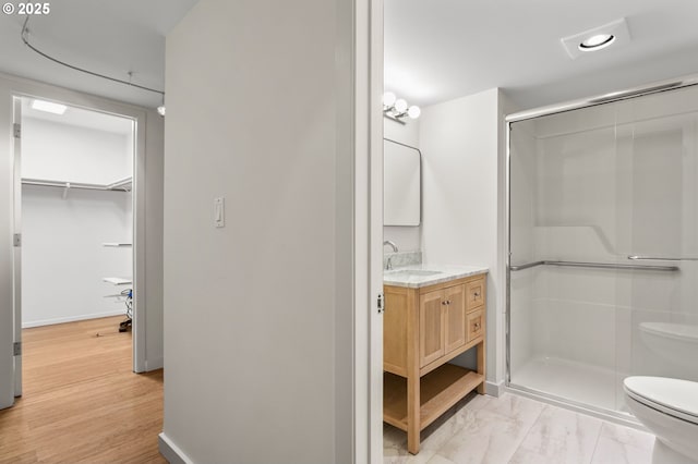 full bathroom with a stall shower, toilet, vanity, and baseboards