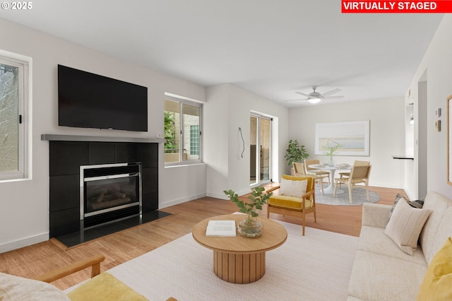 6685 W Burnside Rd Unit 310, Portland, OR 97210 - living room featuring wood finished floors, a tiled fireplace, and a ceiling fan