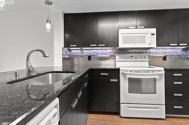 kitchen with white appliances, dark cabinets, light wood finished floors, and a sink