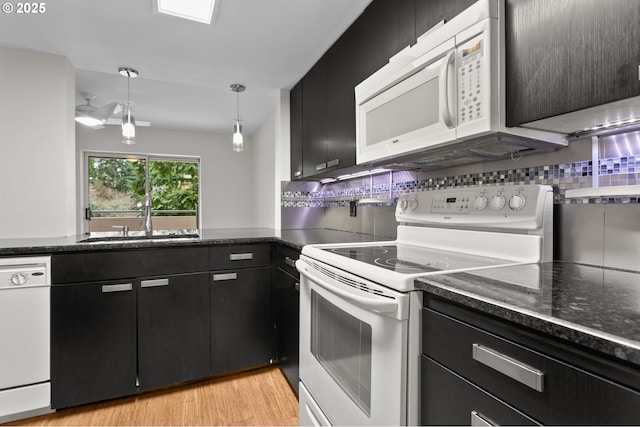 kitchen featuring white appliances, dark cabinets, a sink, light wood-type flooring, and backsplash