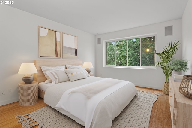 bedroom featuring light wood finished floors, visible vents, and baseboards