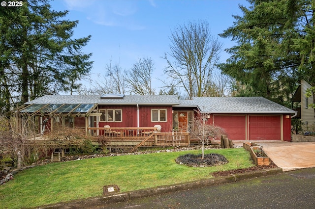 view of front of home with an attached garage, concrete driveway, a shingled roof, and a front yard