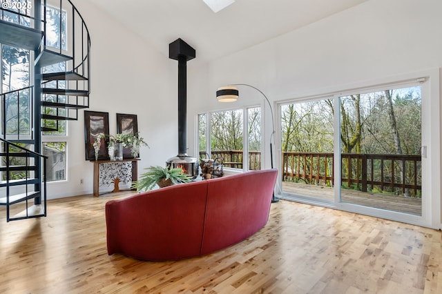 living area with stairs, a towering ceiling, wood finished floors, and a wood stove